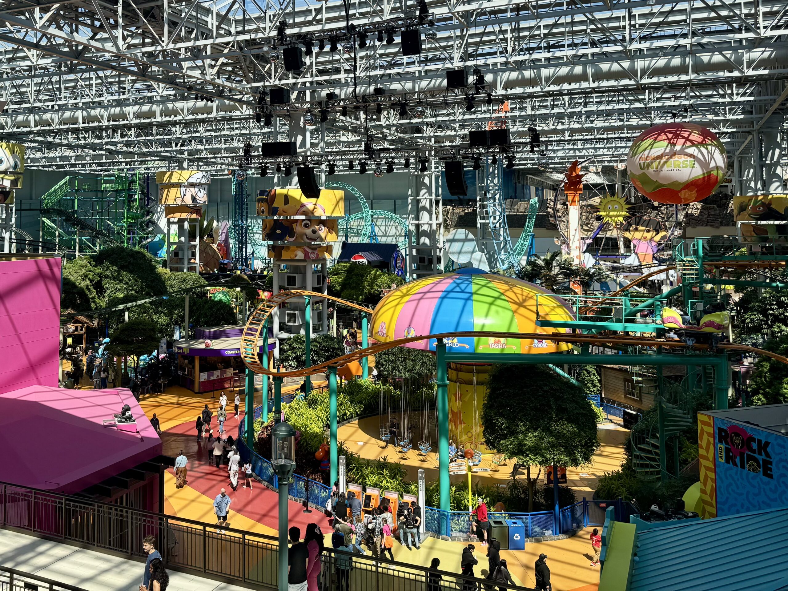 A bright indoor amusement park with roller coaster track weaving above visitors inside Mall of America