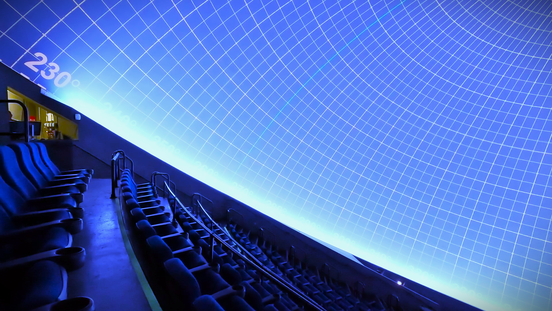 A dome planetarium theater with visitors reclining in seats while a star field glows overhead