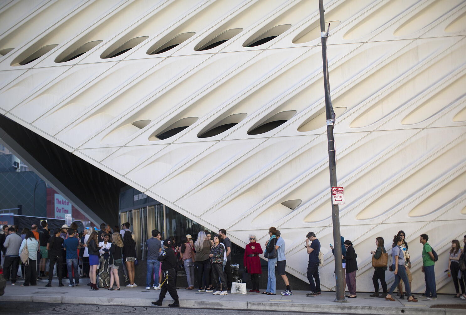 A small group of tourists waiting at a museum entrance with timed-entry tickets open on their phones, morning light on the building facade