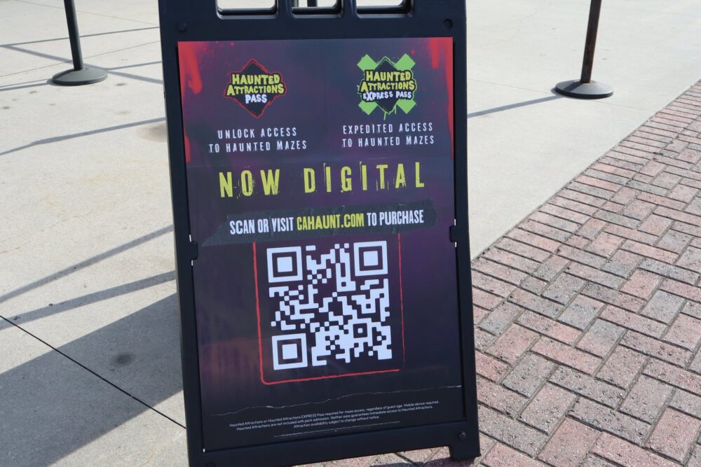 A traveler holding a smartphone showing a digital attraction pass QR code while standing near a museum entrance